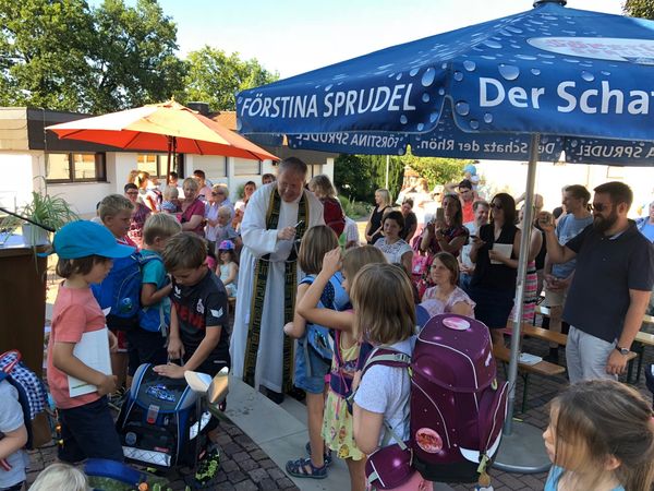 Pfarrer Dagobert Vonderau segnet Schulranzen und Kindergartentaschen